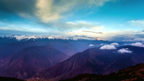 Snow capped mountains under a cloudy blue sky in a scenic landscape Stock Footage 311817592