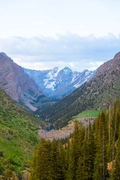 Snow-capped peak framed by a deep, forested mountain valley Stock Photos