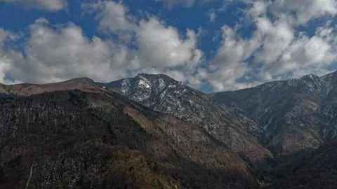 Snow-Capped Peaks and Rugged Mountain Slopes Under a Dynamic Sky Stock Footage 313432438