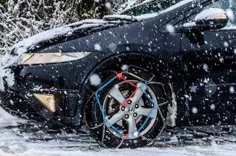 Snow Chains on Front Wheels of a Black Honda Civic During Snowfall on Winter Stock Photos