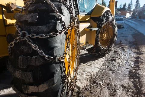 Snow chains have been fitted to heavy duty tyres of a snow clearing vehicle. Stock Photos