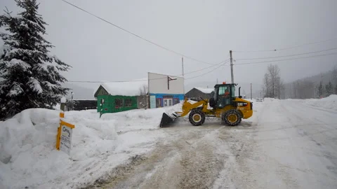 Snow clearing - a front-end loader clears snow from a rural driveway, 4k Stock Footage 169901337