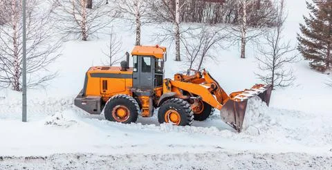 Snow clearing. Tractor clears the way after heavy snowfall. Stock Photos