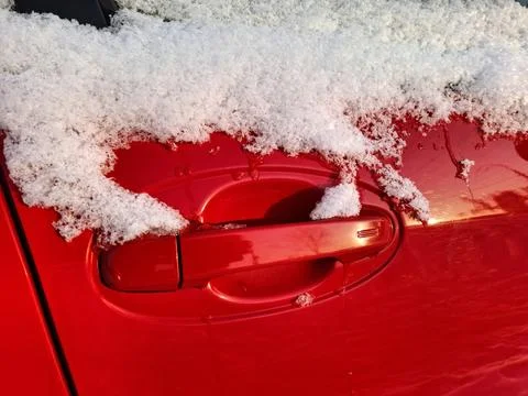Snow clings to the side window and door handle of the red car Photos