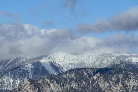 Snow-Covered Alpine Mountain Range with Dramatic Clouds and Blue Sky Stock Photos