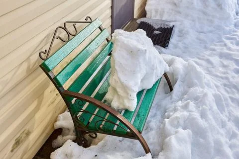 Snow-covered bench thaws in spring in countryside. Stock Photos