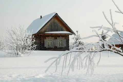 Snow covered branch in front of rustic wooden house at winter Stock Photos