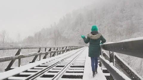 The snow-covered bridge has become a fabulous place for a young woman who walks Stock Footage 254522216