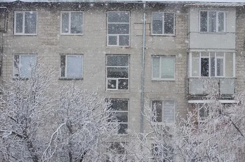 A snow covered building with a tree in front of it.  Stock Photos