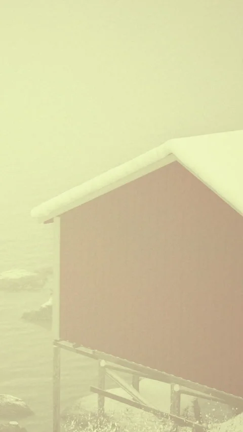 Snow covered cabin by the water during foggy winter morning in Norway Stock Footage 339104907