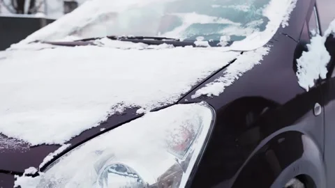 Snow-covered car front with headlight and windshield crusted by frost after Video stock 327521622