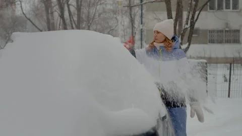 Snow-covered car gets cleared by woman in winter weather Stock Footage 316488874