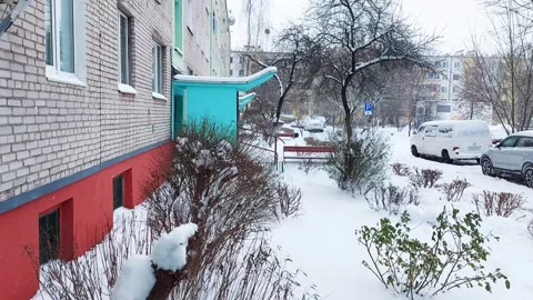 Snow-covered courtyard of multi-storey buildings against the backdrop of cars Stock Footage 295604958