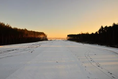 Snow-covered field between forests at the edge of the frame. Stock Photos