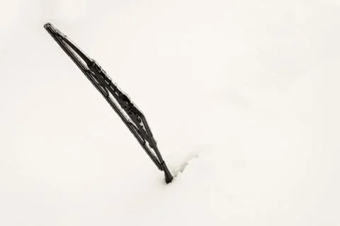 Snow covered front car window glass. Icy car wiper sticking out of snow. Stock Photos