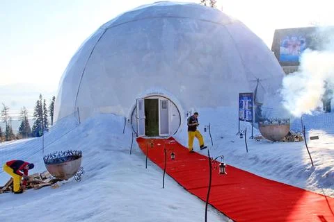 A snow-covered geodesic dome structure with a red carpet at the entrance Stock Photos