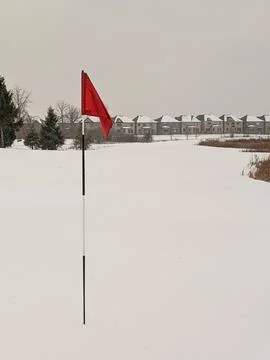 Snow Covered Golf Course with Red Flag and Suburban Houses Stock Photos