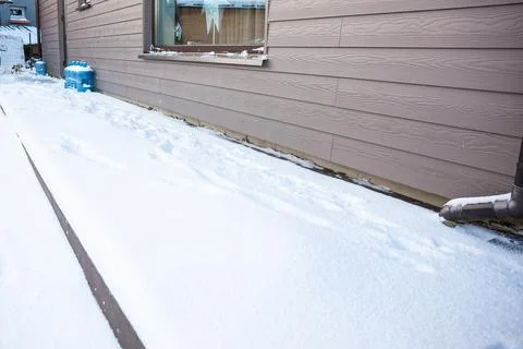 Snow Covered Ground Next to Beige Sided Building in Winter Stock Photos
