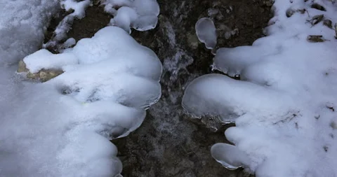 A snow covered ground with a small stream of water Stock Footage 302361403