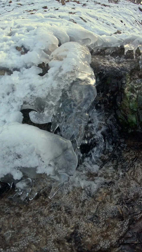 A snow covered ground with a small stream of water 库存影片 302746378