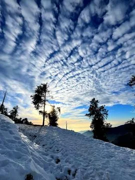 Snow Covered Hills With Dramatic Cloud Pattern and Winter Sunset Light. Stock Photos