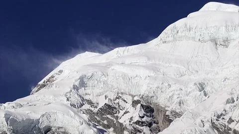 Snow-Covered Himalayan Mountain Peak Under Deep Blue Sky. Snow blowing away.. Stock Footage 311886360