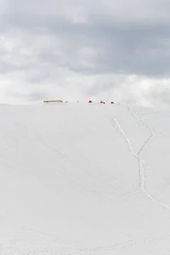 Snow Covered Himalayan Mountain Slope with Small Tents Under Dark Storm Cloud Fotos Stock