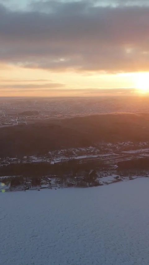 Snow-covered landscape at sunset with distant hills and city lights visible Stock Footage 339286044