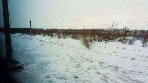 Snow-covered landscape is visible from the window of a passing train Stock Footage 220444209