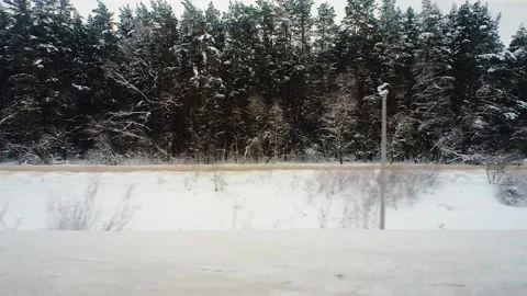 Snow-covered landscape is visible from the window of a passing train Stock Footage 220444382