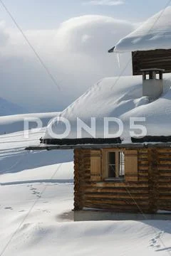 Snow-Covered Log Cabin On A Snow-Covered Slope With Skiing Tracks, Graubuende