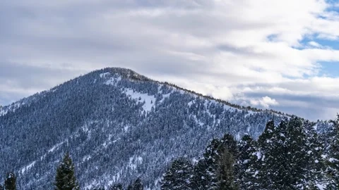 Snow covered mountain with clouds moving by winter Stock Footage 310538063
