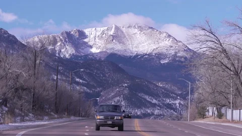 Snow covered mountain with fast moving cars on a highway in the foreground Stock Footage 229434221