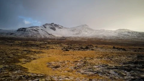 Snow covered mountain fly by over a greenish field Video stock 85625997