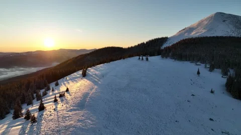 Snow-covered mountain landscape at sunset with serene forest views in winter Stock Footage 319477880