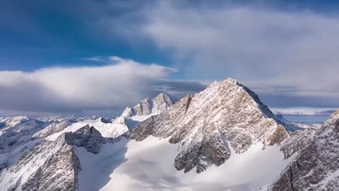 Snow Covered Mountain Peaks Under Partly Cloudy Blue Sky 4K Video stock 332158798