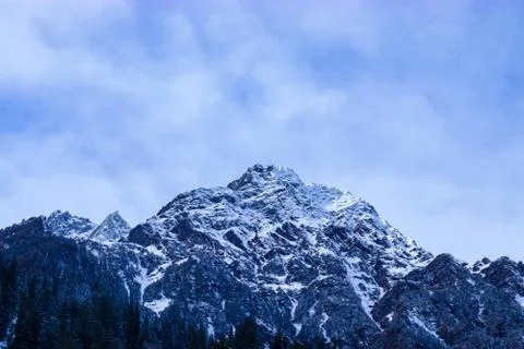 Snow-covered mountain with pine trees at the bottom of the mountain Fotos de archivo
