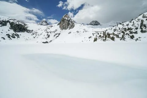 A snow covered mountain range with a large body of water in the foreground Stock Photos