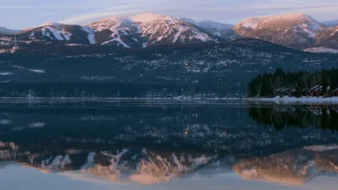 Snow covered mountain range reflecting in a lake at sunset Stock Footage 113236439