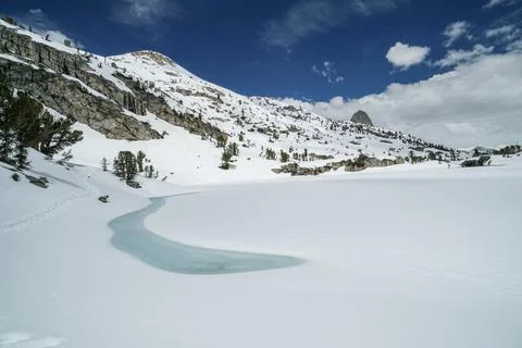 A snow covered mountain range with a small river running through it Stock Photos