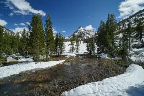 A snow covered mountain range with a small stream running through it Stock Photos