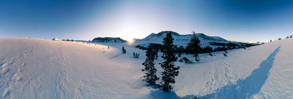 A snow covered mountain range with a tree in the foreground Stock Photos