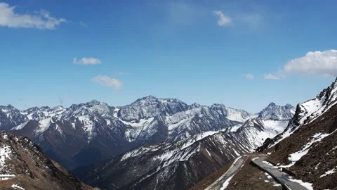 Snow Covered Mountain Range Under Clear Blue Sky With Winding Road Landscape 스톡 동영상 342016345