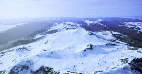 Snow covered mountain range under a clear sky at dawn in winter Illustrazione stock