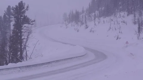 Snow-covered mountain road in winter. Truck in a cloud of snow dust. Stock Footage 72894361