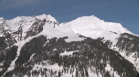 Snow-covered mountain top with treeline 스톡 동영상 10787545
