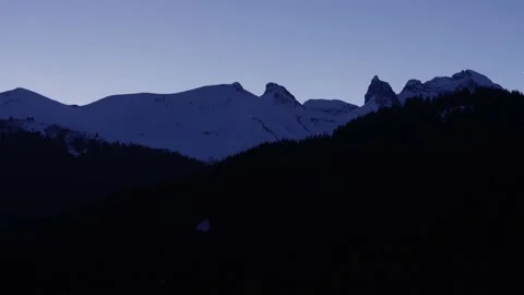 Snow-covered mountains and forests of the Alps at dusk, in Switzerland Stock Footage 239775776