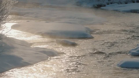 In the snow-covered mountains the river flows, separating steam Stock Footage 123463265