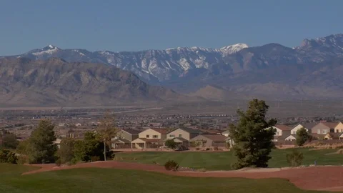 Snow covered mountains surround a putting green golf course B Stock Footage 125344845