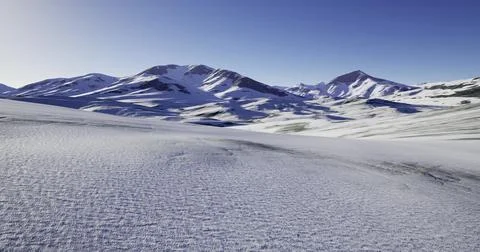 Snow covered mountains under a clear sky at sunrise in a remote location Ilustração Stock